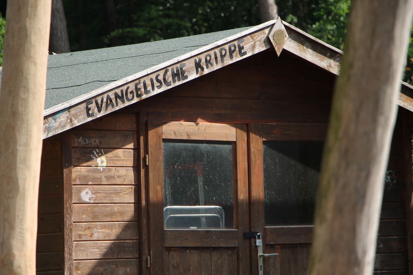 Das Holzhaus der Evangelischen Krippe Aumühle mit Namensschild über der Tür.