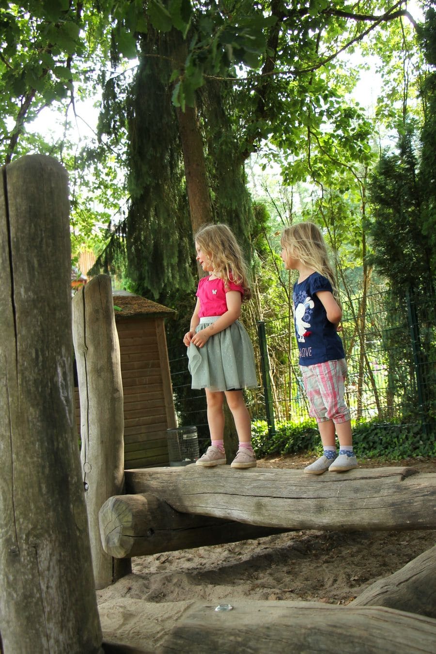 Zwei Kinder stehen am Zaun des Kindergartengeländes.