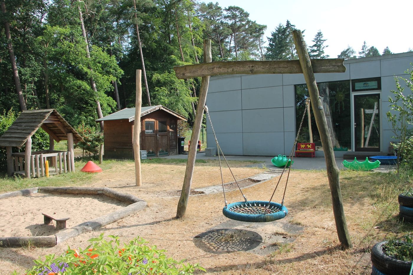 Der Außenspielbereich mit Schaukel, Sandkasten und Spielhäusern.